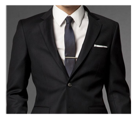 Cropped image of a man wearing a black suit with a white shirt, dark tie, and a tie clip.