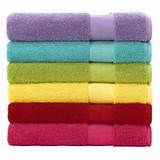 A colorful stack of neatly folded towels consisting of hot pink, red, yellow, green, aqua, and purple towels.